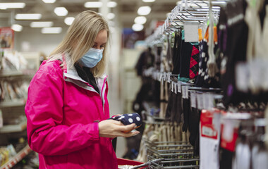 Woman in medical mask is choosing socks.