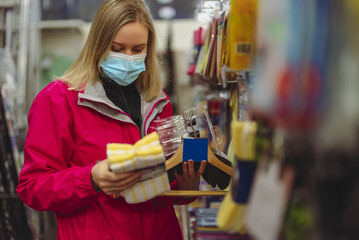 Woman in medical mask chooses rag for floor cleaning.