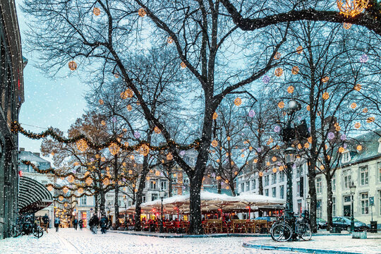 Bars and restaurants with snow and christmas lights on the Onze Lieve Vrouweplein square in Maastricht