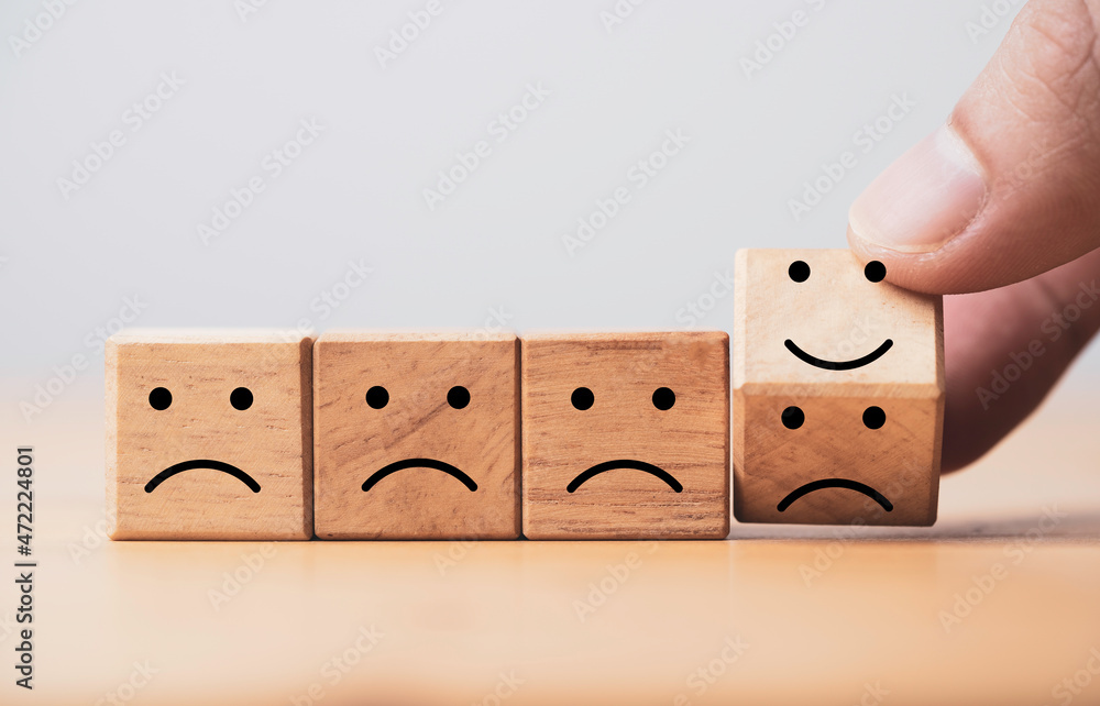 Poster Hand flipping sad face to smile face which print screen on wooden cube block for the best evaluation , customer satisfaction concept.