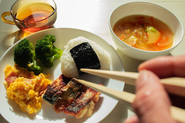 おにぎりの乗ったワンプレートごはんをに箸を向ける手