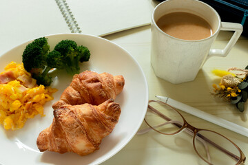 クロワッサンのワンプレートとコーヒーと文房具を並べた画像