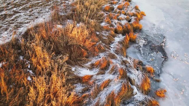 The bank of the frozen river is covered with beautiful white frost, aerial view. In winter, at sunset, in the evening. Screensaver, footage, nature for intro, background, titles. UHD 4K.