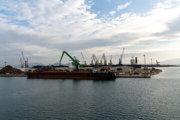 Fototapeta premium harbor crane unloading scrap metal from a freight ship in the industrial port of Ploce