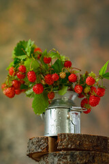 a bouquet of fresh, ripe strawberries in a metal mini vase. Rustic style. Brown background.