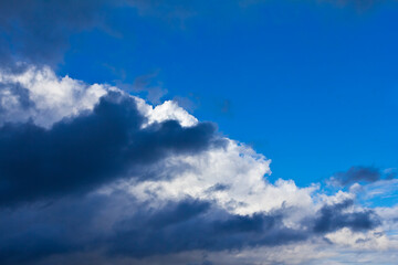 Fototapeta premium Dramatic light and dark clouds against a blue summer sky. Dangerous atmosphere concept background texture.
