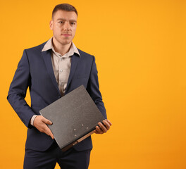 confident man businessman in suit holding folder on yellow background, copy space