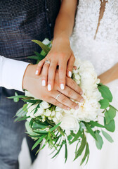 Obraz na płótnie Canvas Hands of the newlyweds on a wedding bouquet. Details.
