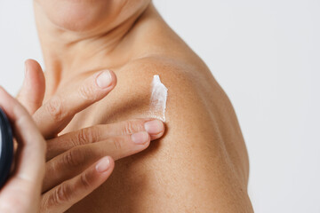 Cropped photo of mature half-naked woman applying body cream