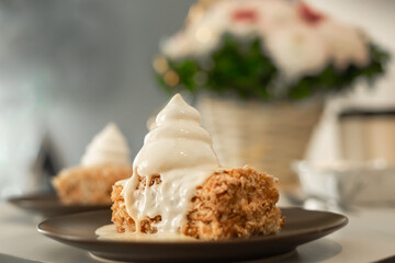 Napoleon cake pieces on black dessert plates with white meringue cream on top. Birthday cake and bouquet on the table.