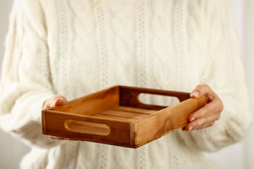 Hands with an empty tray on a background of a white sweater on a Christmas morning 