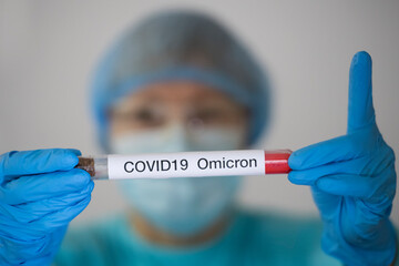 Woman in protective suit holding test tube with sample of analysis suspected to be infected with...