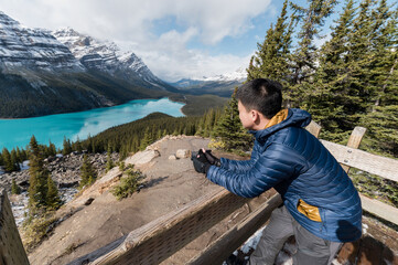 Asian male tourist standing and enjoying the view of Peyto Lake at viewpoint