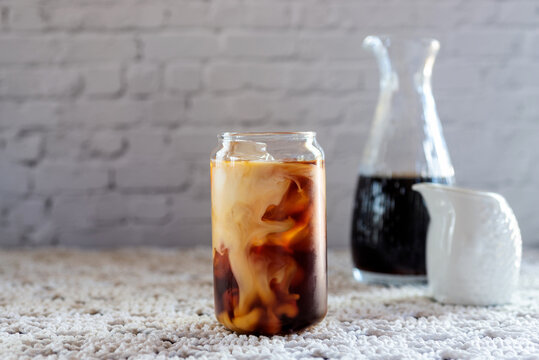 a glass of cold brew coffee with milk on white table background.
