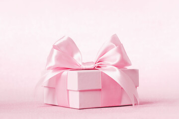 Pinkgift box with shining pink ribbon bow on pink background. Gift or holiday concept. Mothers Day,...