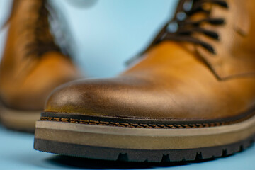 New pair of winter leather boots on a light blue background. Front view, close-up. Fashionable concept.
