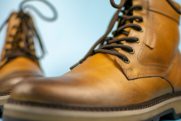 New pair of winter leather boots on a light blue background. Front view, close-up. Fashionable concept.