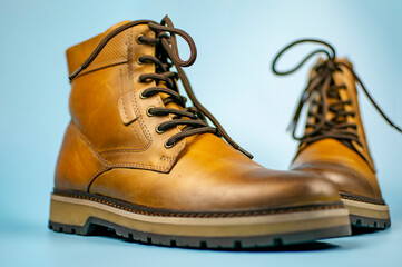 New pair of winter leather boots on a light blue background. In various positions, front view. Fashionable concept.