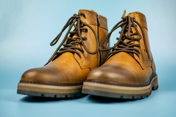 New pair of winter leather boots on a light blue background. In various positions, front view. Fashionable concept.