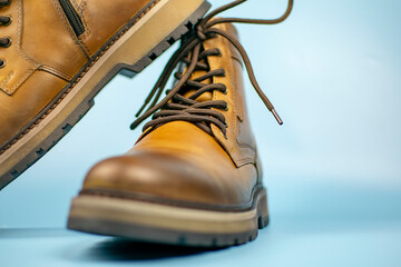 New pair of winter leather boots on a light blue background. One shoe is located on top of the other, front view. Fashionable concept.