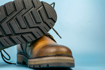 New pair of winter leather boots on a light blue background. One shoe is located on top of the other, front view. Fashionable concept.