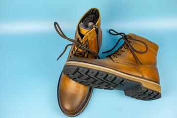 New pair of winter leather boots on a light blue background. View from above. Fashionable concept.