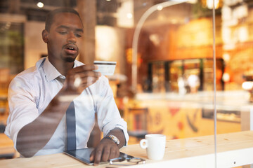 Businessman in cafe holding a credit card. Guy making online payment. Man paying the bill in cafe with a credit card.