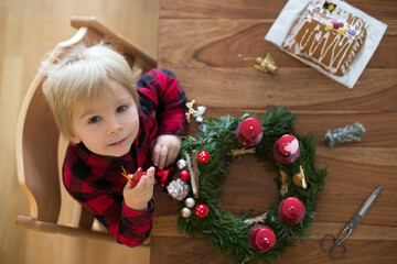 Little cute blonde toddler boy, making advent wreath at home