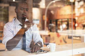 Businessman in cafe holding a credit card. Guy making online payment. Man paying the bill in cafe with a credit card.