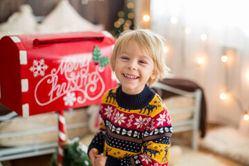 Cozy christmas atmosphere at home, child sitting on the bed, eating cookies with his little pet dog, maltese dog, enjoying christmas together