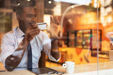 Businessman in cafe holding a credit card. Guy making online payment. Man paying the bill in cafe with a credit card.