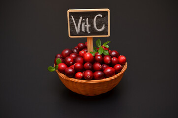 fresh red berries cranberries and inscription vitamin C on a dark background
