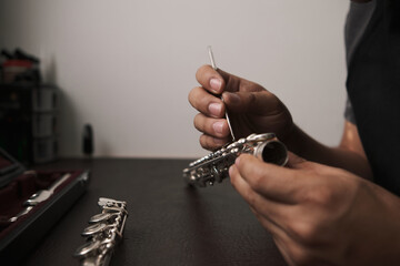 Hands of a man disassembling the keys of a flute to repair it.