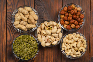 Pistachios, hazelnuts, peanuts, pumpkin seeds, cashews on a wooden table. Nut diet.