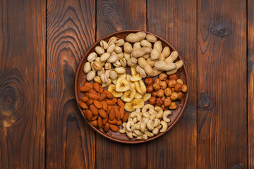 cashew nuts, hazelnuts, peanuts, banana, almonds on a wooden table