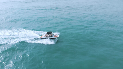 a view of the speedboat from a height to its right as it goes with its marked thigh and makes foam from the sea. High-quality photo