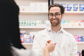 Female asian client customer buyer in pharmacy giving male caucasian handsome pharmacist druggist medical prescription for medications, drugs, painkillers, antibiotics, pills