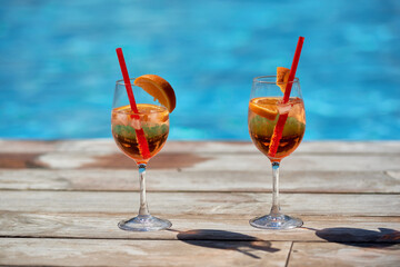 Aperol spritz cocktails on summer party by the pool, copy space. Event celebration concept. Traditioanal italian aperitif.