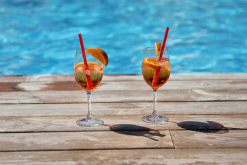 Aperol spritz cocktails on summer party by the pool, copy space. Event celebration concept. Traditioanal italian aperitif.