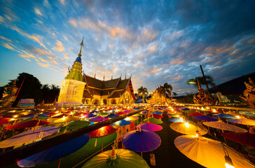 Northern Thailand Temple on Loi Krathong day (Yi Peng Festival) with many colored umbrellas in the foreground in the evening.