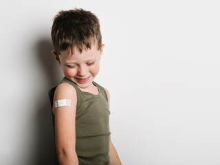 Cheerful schoolboy after vaccination with band aid on arm