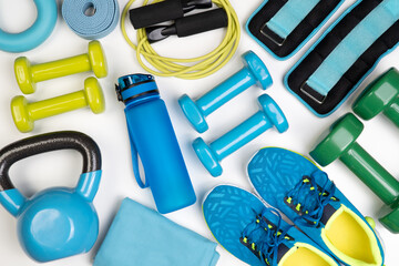 Dumbbells, trainers, jumping rope and other fitness equipment on white background, top view