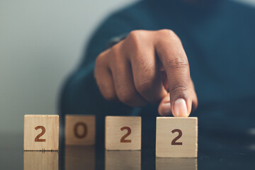 Businessman pointing wooden block with text. Calendar concept 2022 start new year business plan.

