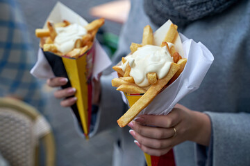 Belgian frites or french fries with mayonnaise in Brussels, Belgium. Female tourist holds two...