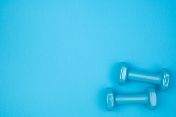 Blue dumbbells on blue background, top view with copy space