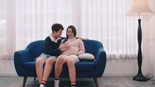 Pregnant Asian lesbian woman and her partner are happy to spend time together at home.