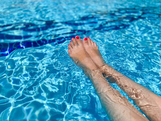 female feet in the water, beautiful bright blue water, texture of the blue water surface