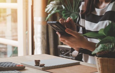 woman's hands using smartphone on desk table. business concept. monthly home expenses, taxes, bank...