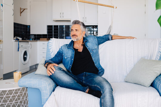 Aged wistful man sitting on sofa