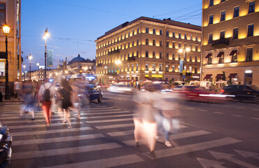 evening city street, cars and people are blurred in motion, long exposure